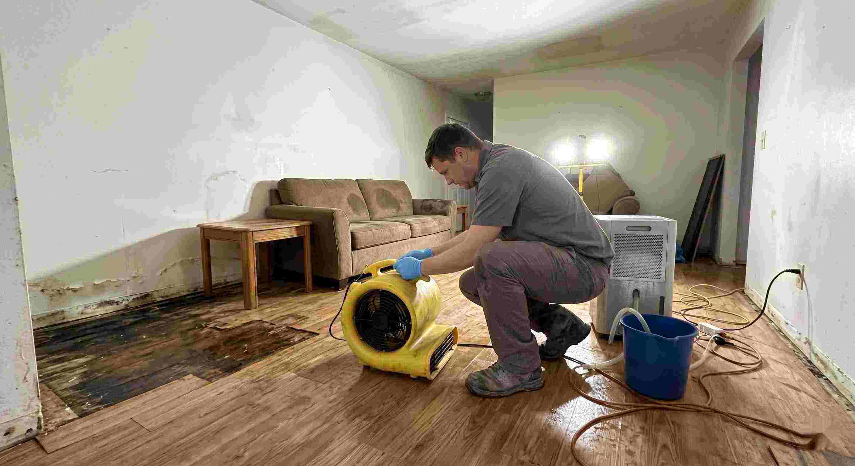Trusted water damage restoration technician drying wet floors with equipment during cleanup process in Susanville